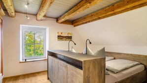 A bedroom with a wooden bed, a window with a view of trees, and a wooden desk. - Apartment 'Gästehaus Wüpping 3' with Mountain View, Private Terrace and Wi-Fi (Salem)