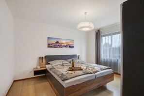 Ein modernes Schlafzimmer mit Bett, Nachttisch und einer Pendelleuchte.