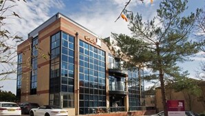 A modern hotel with a glass facade, a brick base, and a sign indicating it is a hotel.