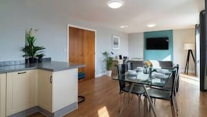 A modern kitchen with a central island, wooden cabinets, and a dining area with a glass table and chairs.