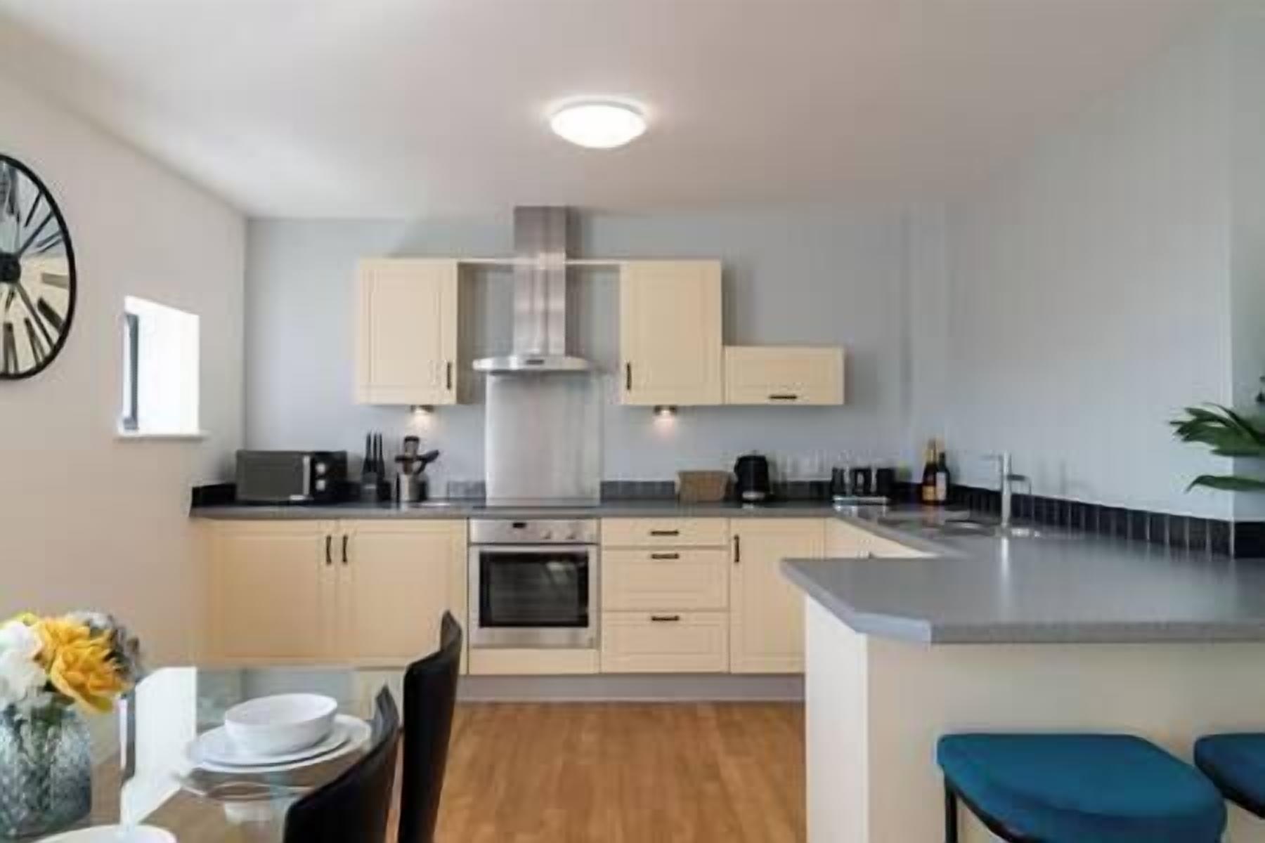 A modern kitchen with light-colored cabinets, a central island, and a dining area with a table and chairs.