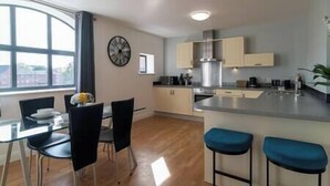 A modern kitchen with a large island, bar stools, and a dining area with chairs and a table.