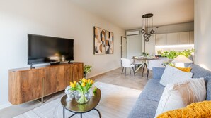 Una sala moderna con un televisor de pantalla plana, un mueble de madera y un comedor con mesa y sillas.