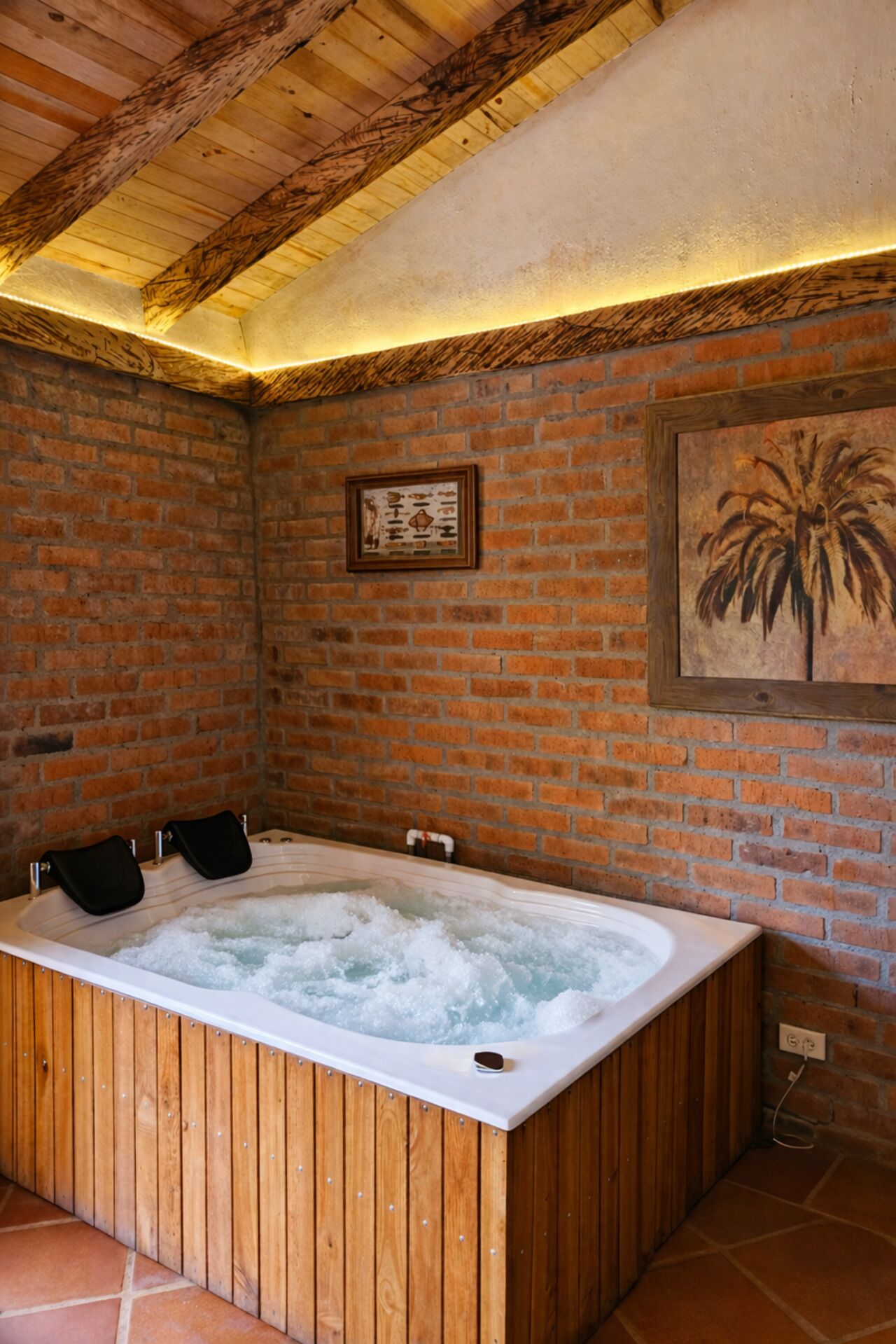 A hot tub in a room with brick walls and wooden beams.