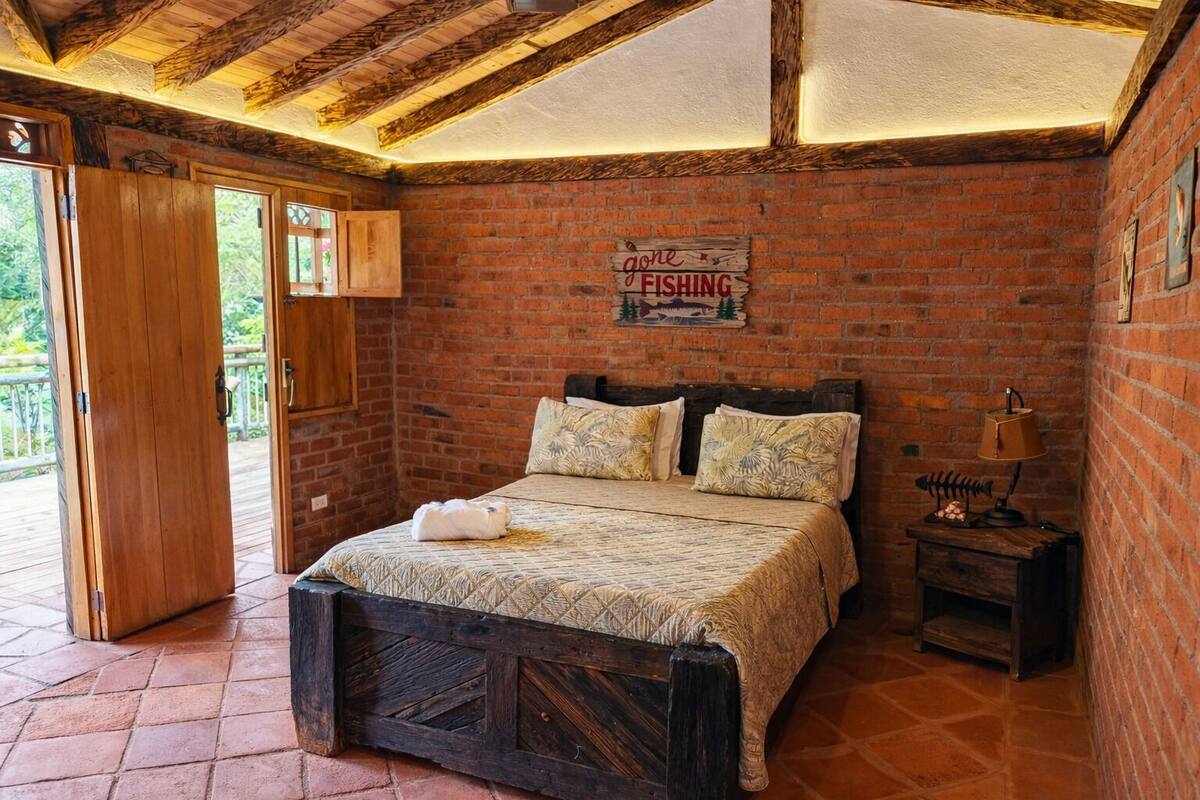A rustic bedroom with a wooden bed, a brick wall, and a sign indicating the room is no longer available for fishing.