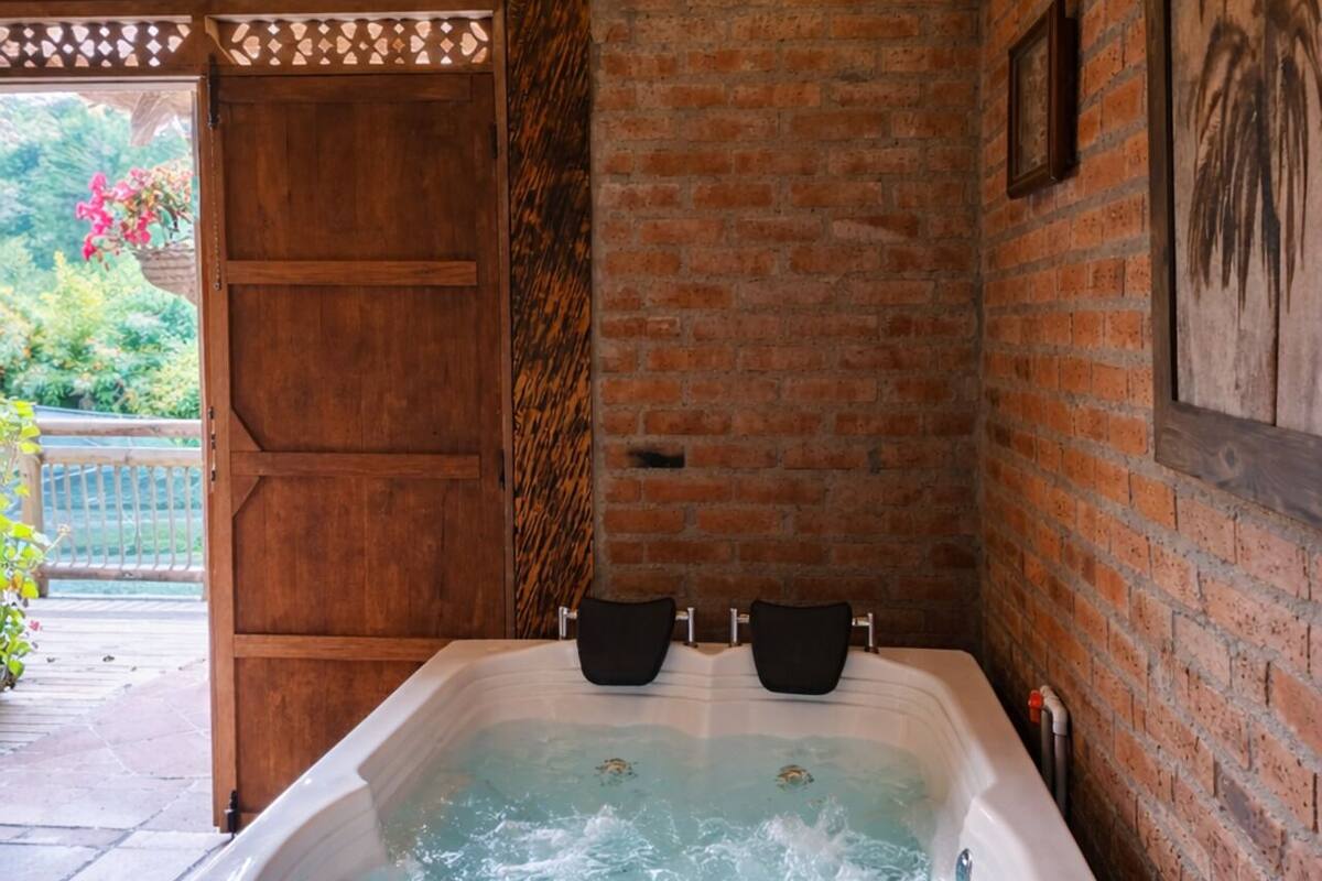 A hot tub with wooden exterior, a brick wall, and a wooden ceiling.
