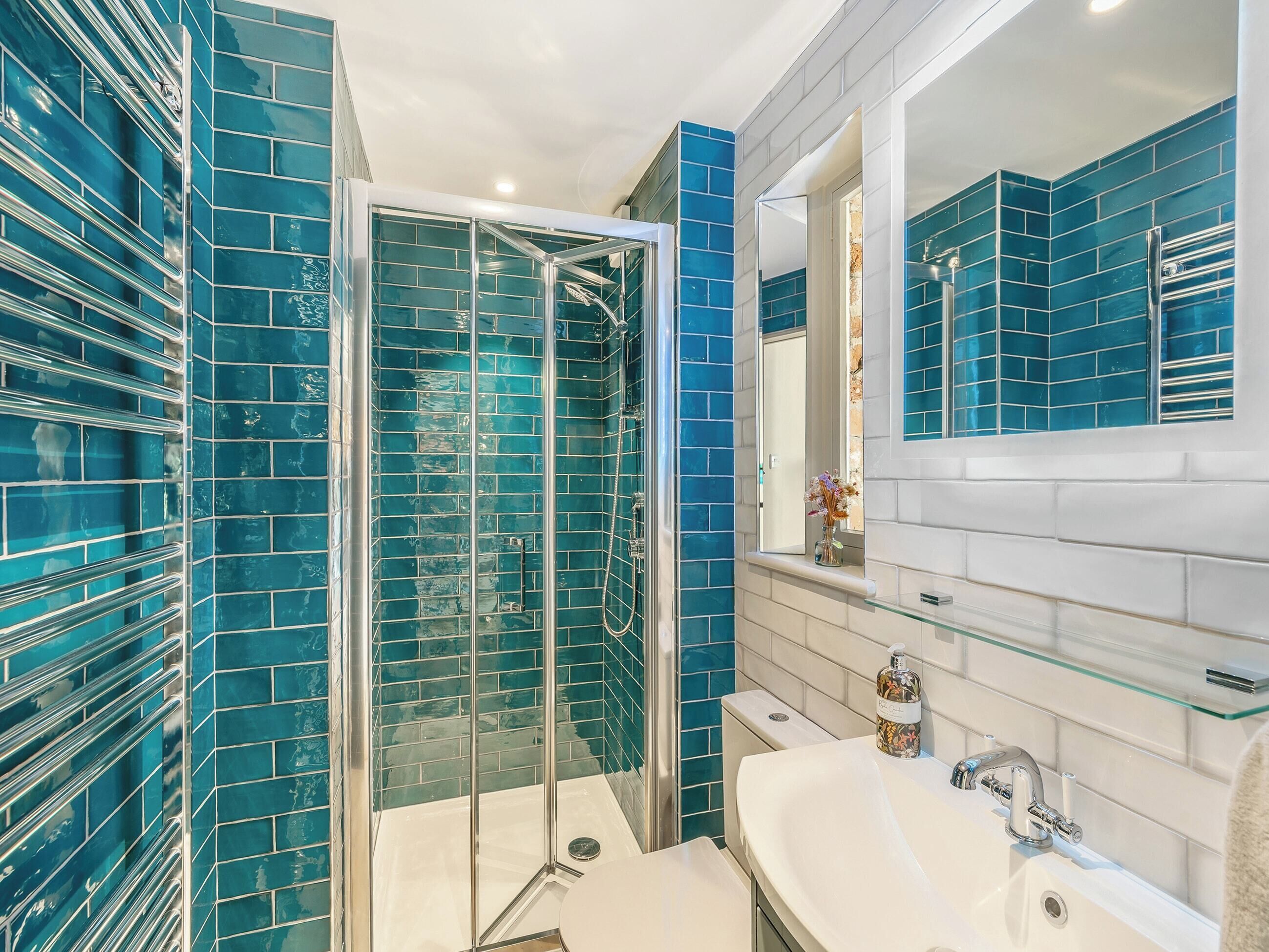 A bathroom with a glass-enclosed shower, a white sink, and blue-tiled walls.