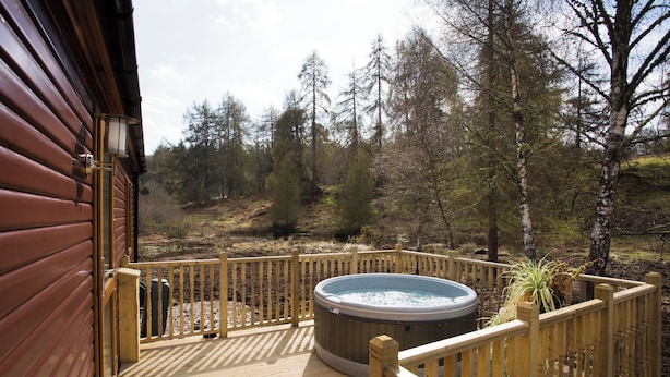 A wooden deck with a hot tub, surrounded by a wooden fence and trees. - Bluebell Lodge - Sleeps 4,hot Tub, Loch & Woodland (Strathpeffer)