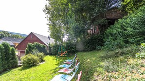 Une cour arrière verdoyante avec une balançoire, une rangée de chaises et une grange rouge.