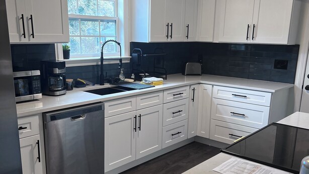 Una cocina moderna con armarios blancos, electrodomésticos de acero inoxidable y un salpicadero negro.