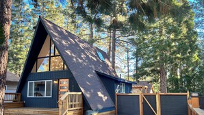 A modern, triangular-shaped cabin with a wooden deck and a garage.