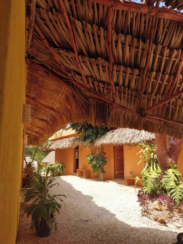 A thatched-roof structure with a gravel courtyard and potted plants.
