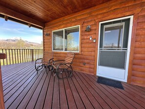 A wooden deck with two rocking chairs and a window with a mesh screen. - Mount Peale Country Inn near Moab (La Sal)