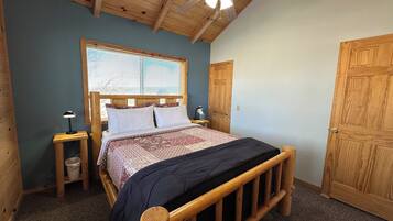 A bedroom with a wooden bed, a ceiling fan, a window with blinds, and a door.