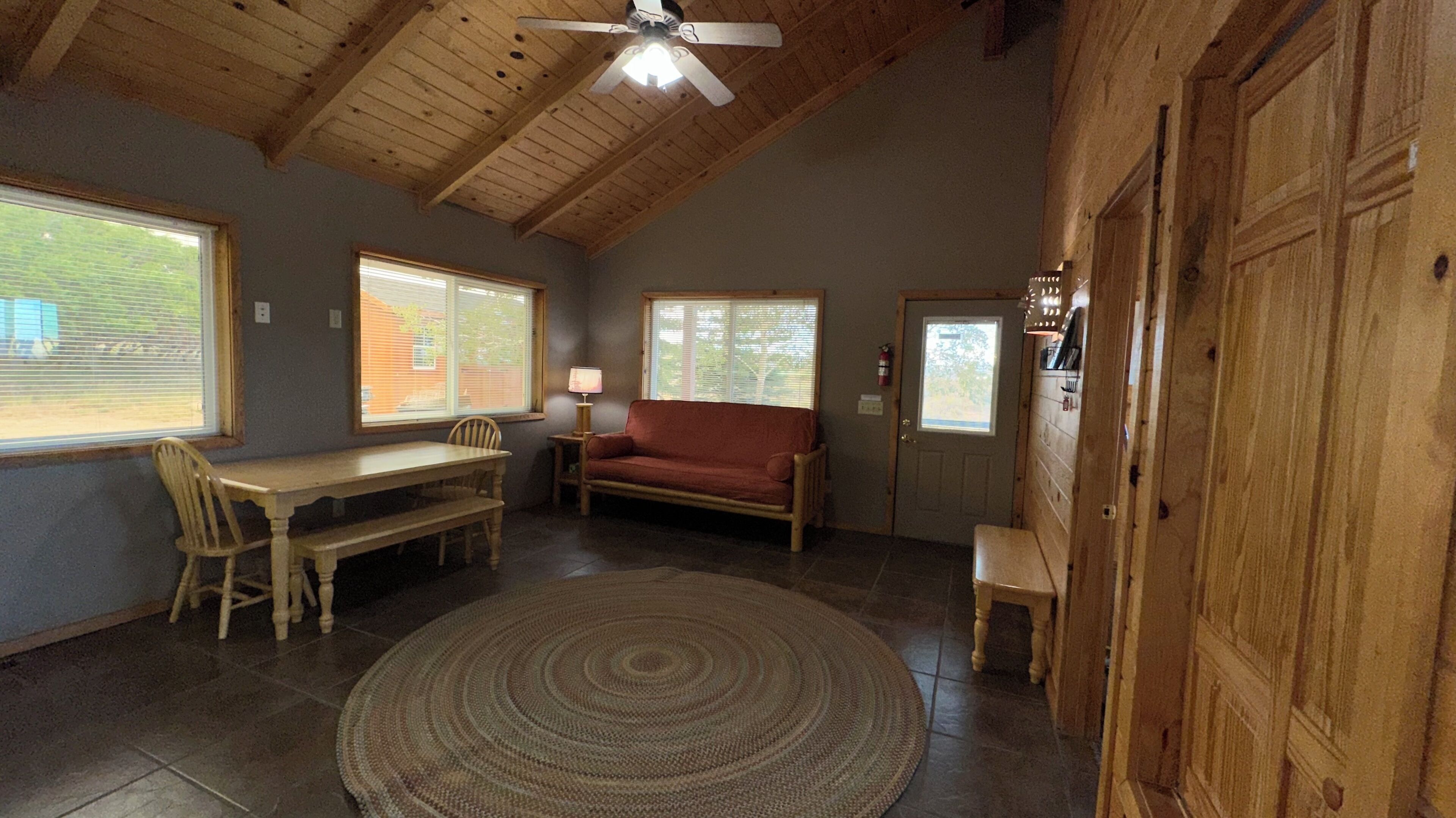 Ein Zimmer mit Holzboden, einer Couch, einem Esstisch mit Stühlen und einem Teppich.