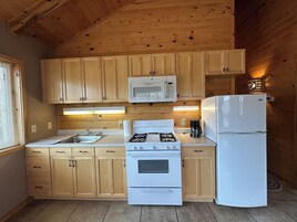 Una cocina compacta con armarios de madera, microondas, estufa y refrigerador.