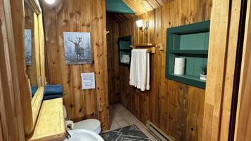 Un baño de madera con lavamanos, inodoro y espejo.