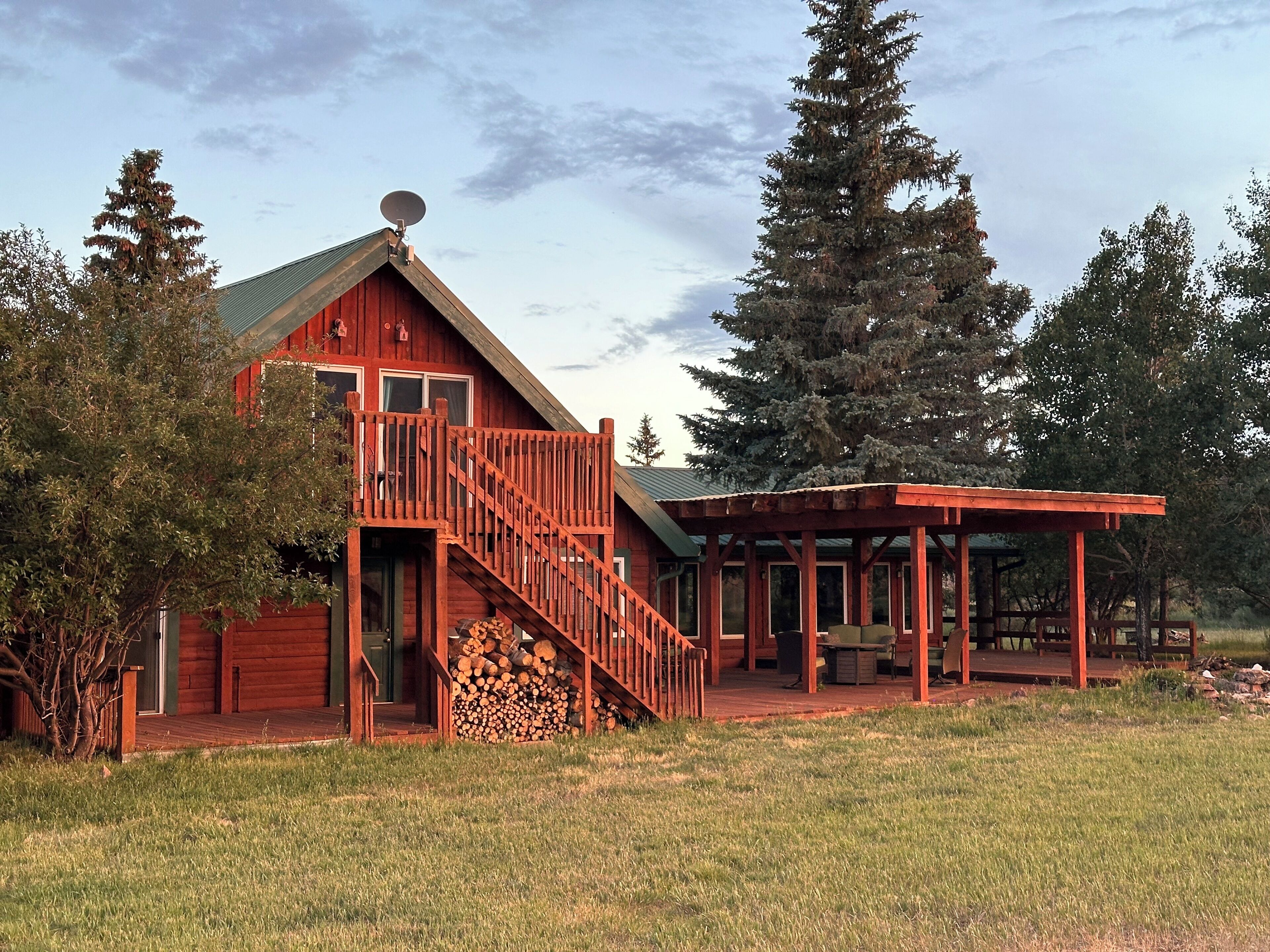 Eine Holzhütte mit überdachter Veranda und einer Treppe zu einer Terrasse.