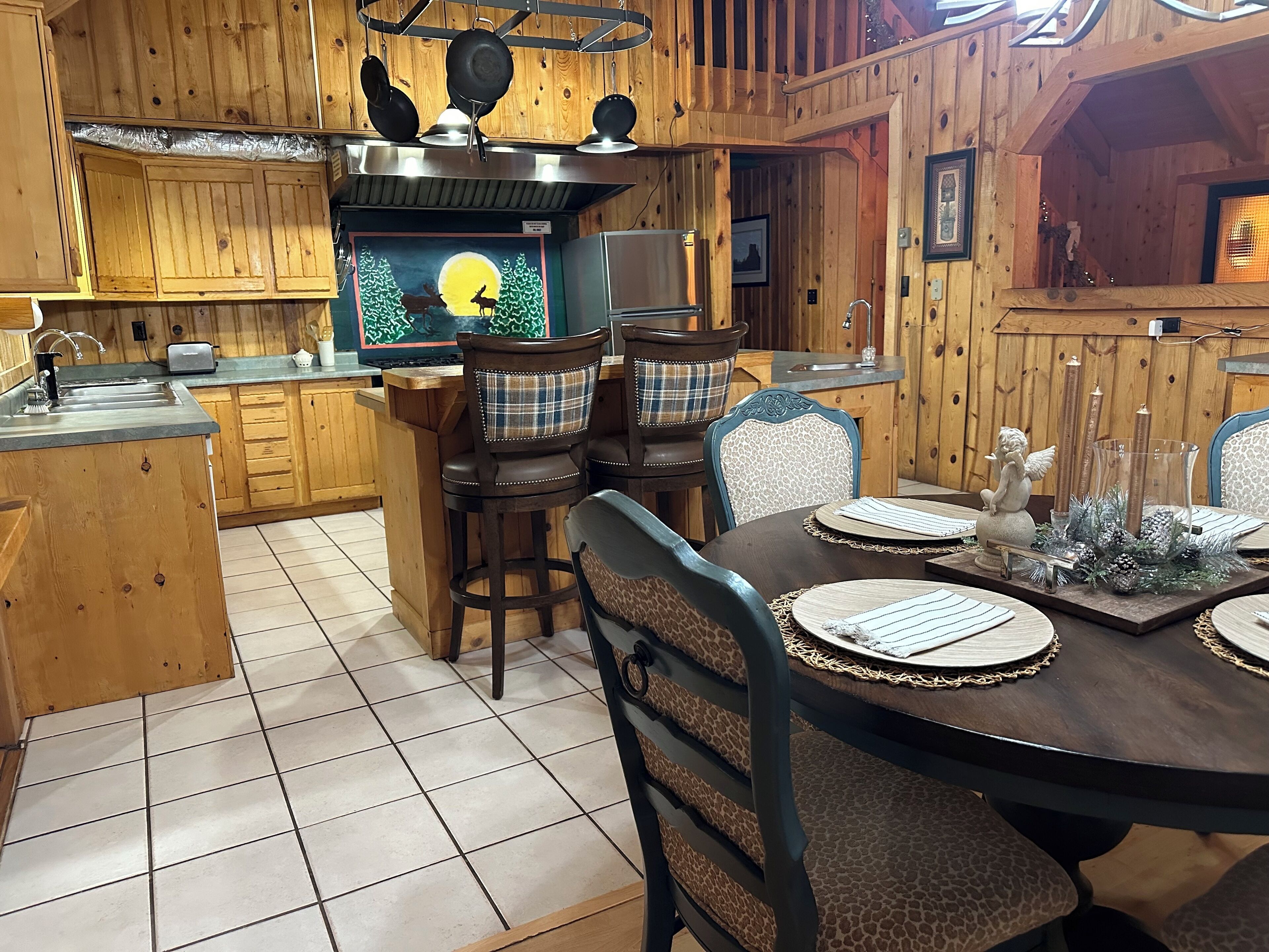 A wooden cabin interior with a kitchen area, dining table, and chairs.