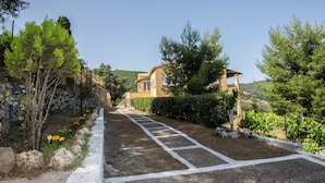 A residential property with a paved driveway, a house with a brown facade, and surrounding greenery. - Giannis House 2022 by Corfu Escapes (Corfu)