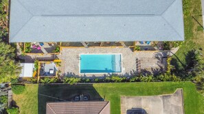 An aerial view of a residential property with a swimming pool, patio area, and surrounding greenery. - 400 South (Cocoa Beach)