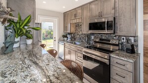 Una cocina moderna con encimeras de granito, electrodomésticos de acero inoxidable y un salpicadero de piedra.