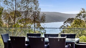 An outdoor seating area with a view of a body of water and hills. - Coastal View (Lorne)