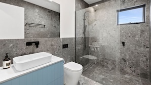 A modern bathroom with a freestanding bathtub, a toilet, and a glass-enclosed shower area. - Coastal View (Lorne)