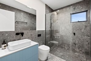 Un baño moderno con una bañera independiente, un inodoro y una zona de ducha con mampara de vidrio.