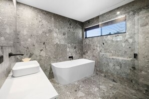 Ein modernes Badezimmer mit zwei Waschbecken, einer freistehenden Badewanne und einem Fenster mit Blick.