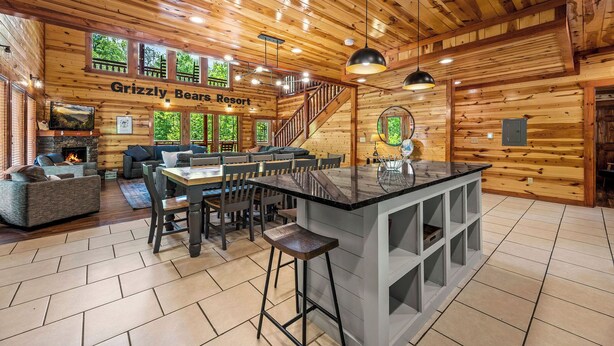 Interior acogedor de una cabaña con chimenea, paredes de madera, un comedor y una barra con taburetes.