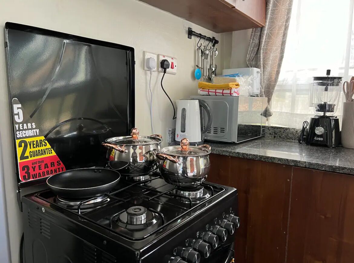 A kitchen with a stove, pots, a microwave, and a blender.
