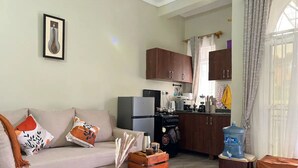 A living room with a sofa, coffee table, and a framed picture on the wall. - Theoscozyhaven (Kampala)