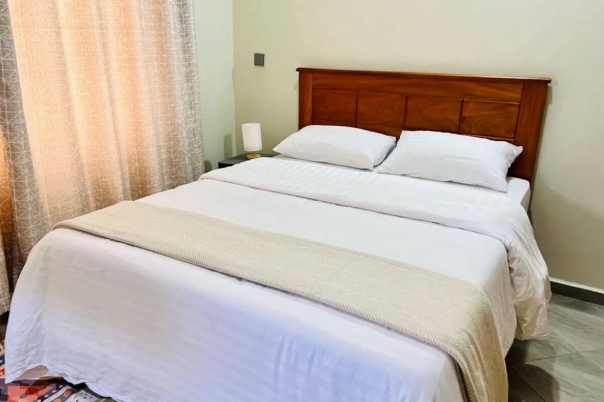 A neatly made bed with a wooden headboard, white bedding, and a bedside lamp.