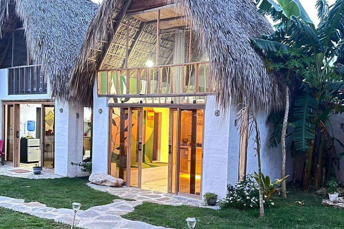 A resort with thatched-roof structures, a stone pathway, and tropical vegetation.