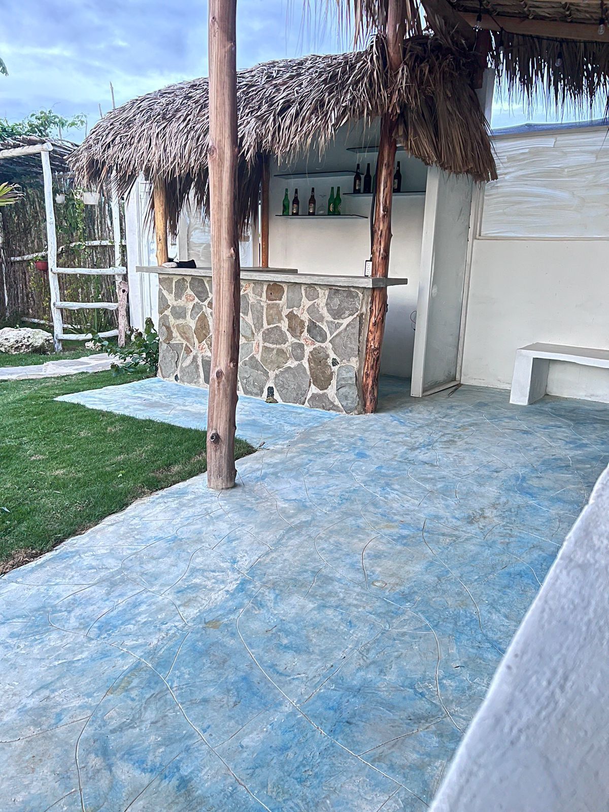 Een terras met een stenen muur en een rieten dakconstructie.