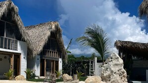 Un complejo turístico con edificios de techo de paja, una piscina cristalina y exuberante vegetación tropical.