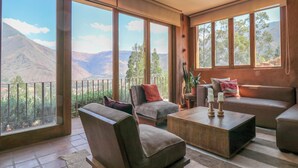 A spacious living room with large windows offering a mountain view, a comfortable sofa, and a coffee table. - Catahuasi by Wynwood House (Huayllabamba)