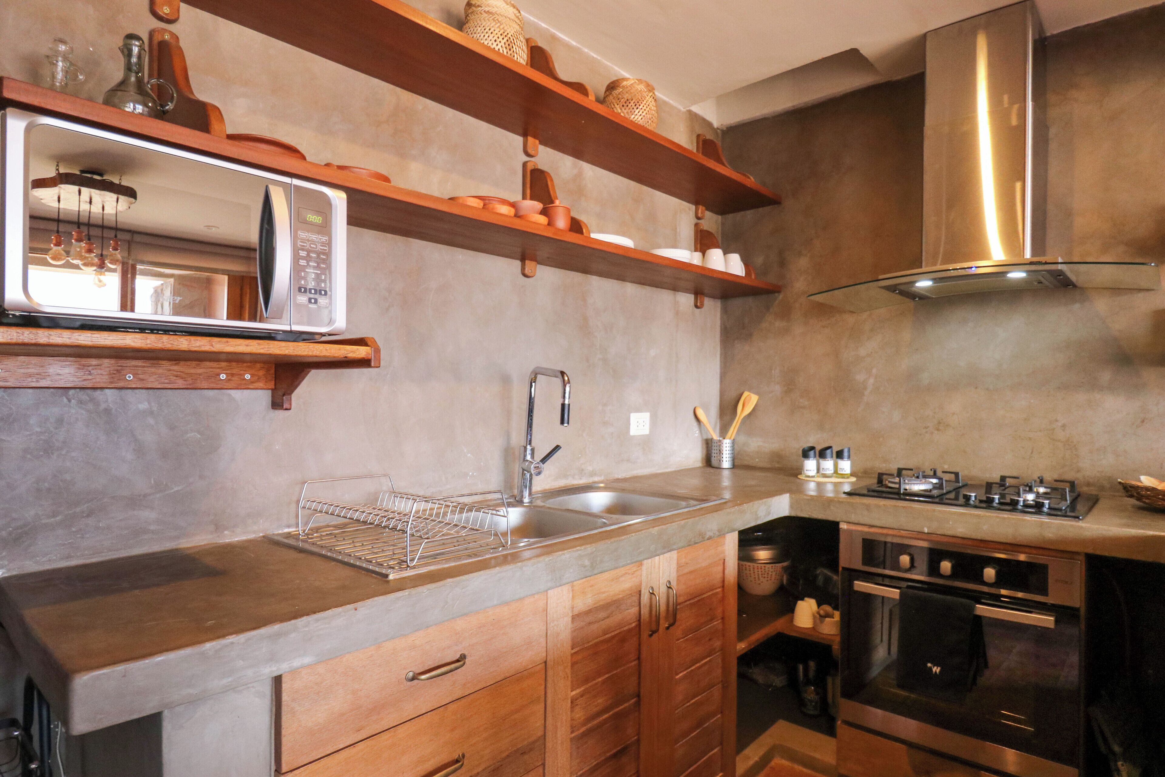 A kitchen with wooden cabinets, a stainless steel oven, a microwave, and a sink.