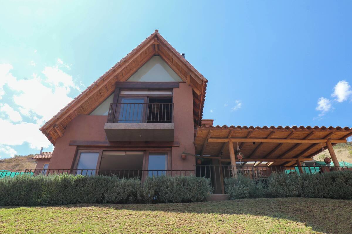 A two-story house with a balcony, a covered patio, and a well-maintained lawn.