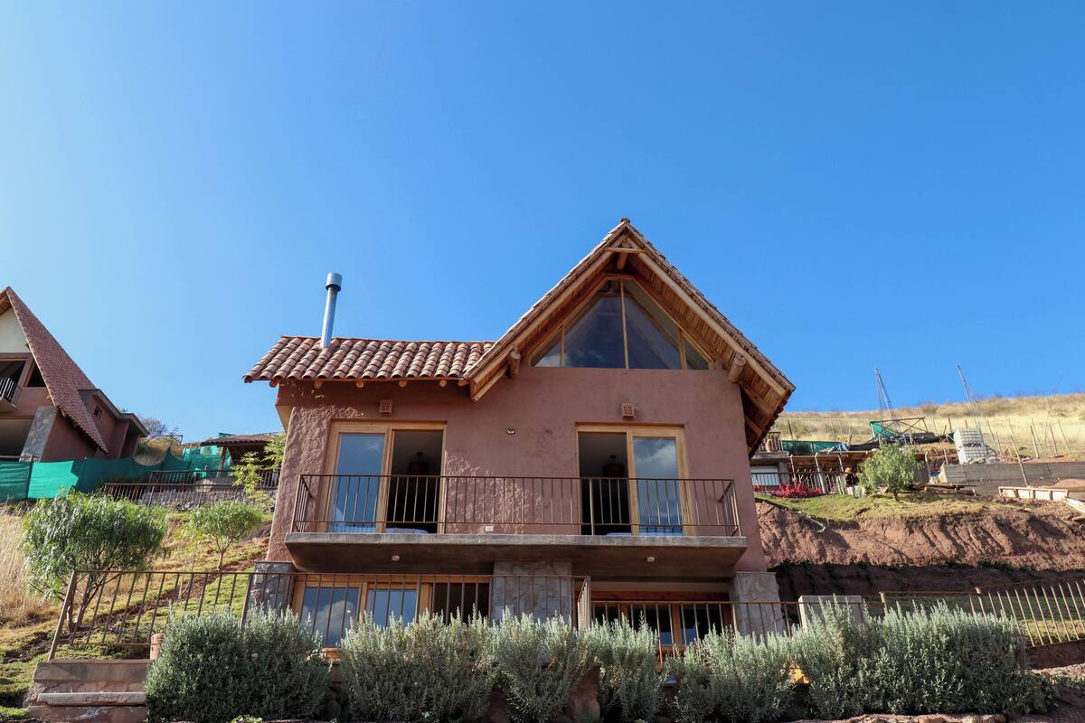 A two-story house with a balcony, a chimney, and a clear blue sky.