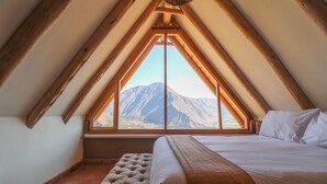 A bedroom with a large window, wooden beams, a bed, and a bench. - Catahuasi by Wynwood House (Huayllabamba)