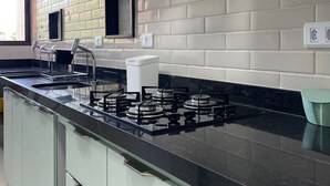 A modern kitchen with a black countertop, gas stove, and white cabinets. - Flat 2 quartos no Dubourcq Residence  (Ipojuca)
