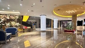 A modern lobby with a polished marble floor, a reception desk, and a seating area with blue chairs. - Baili Hotel (Changshan)