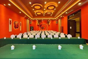 A conference room with a green carpet, white chairs, and a table with teapots. - Baili Hotel (Changshan)