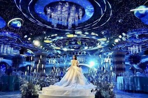 Un intérieur futuriste avec une plateforme circulaire centrale et une personne vêtue d’une robe blanche.