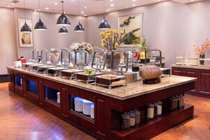 Montaje de bufé con varias estaciones de comida, un jarrón decorativo en el centro e iluminación colgante.