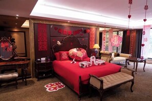 Une chambre d’hôtel avec un grand lit, une tête de lit en bois, une table de chevet, une chaise et un miroir.
