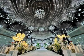A spacious interior with a central aisle, decorative chandeliers, and floral arrangements.