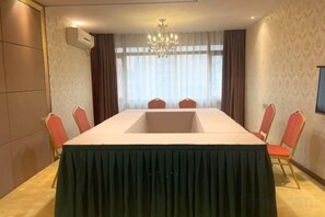 A conference room with a long table, red chairs, a chandelier, and a large window with curtains. - Baili Hotel (Changshan)
